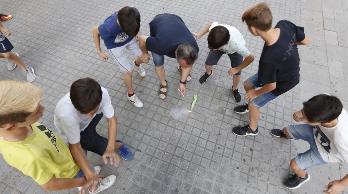 Unos chicos tiran petardos con un adulto, en Barcelona.