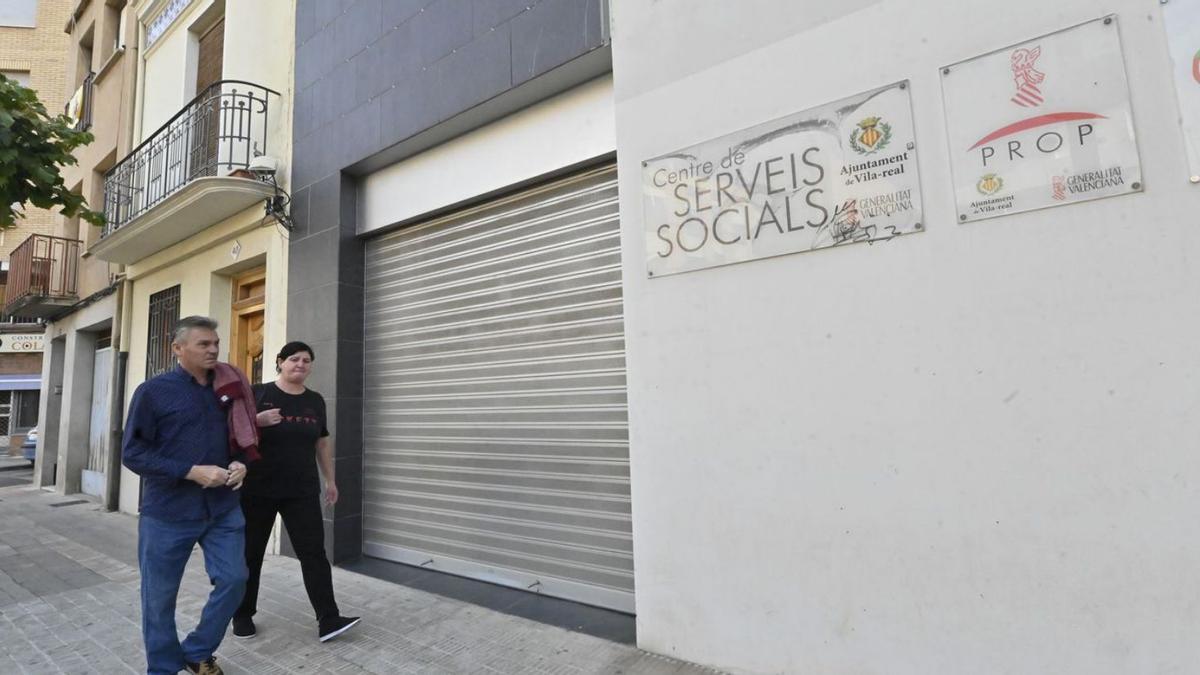 Dos personas pasan por delante de la puerta del servicio de Servicios Sociales, ubicado en la calle Josep Ramon Batalla. | MANOLO NEBOT