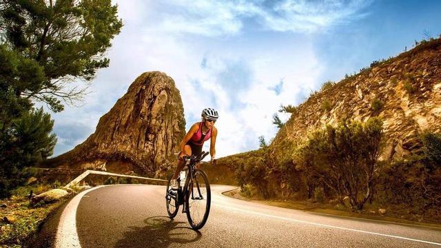 Imagen promocional en la que una ciclista pedalea por una carretera gomera.
