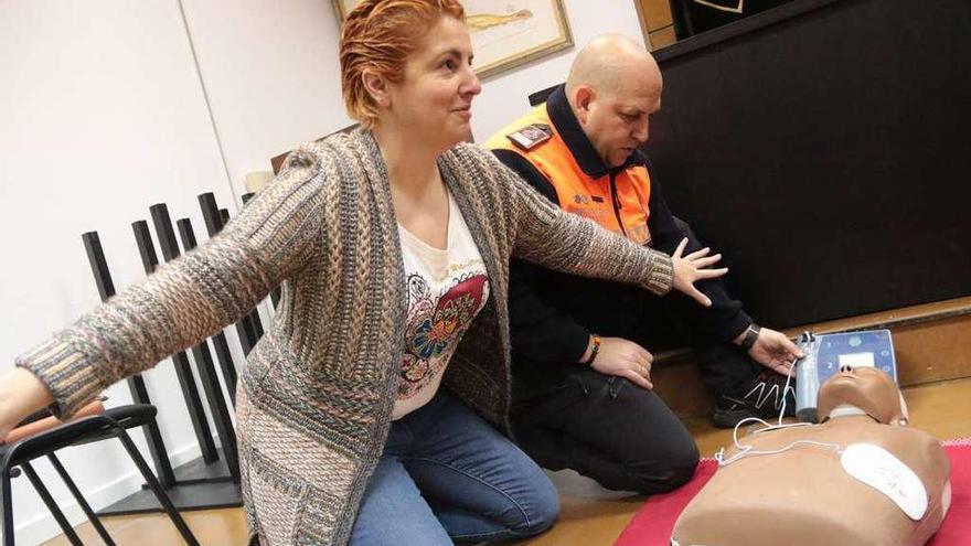 Montse González muestra cómo funciona el desfibrilador apoyada en un maniquí.