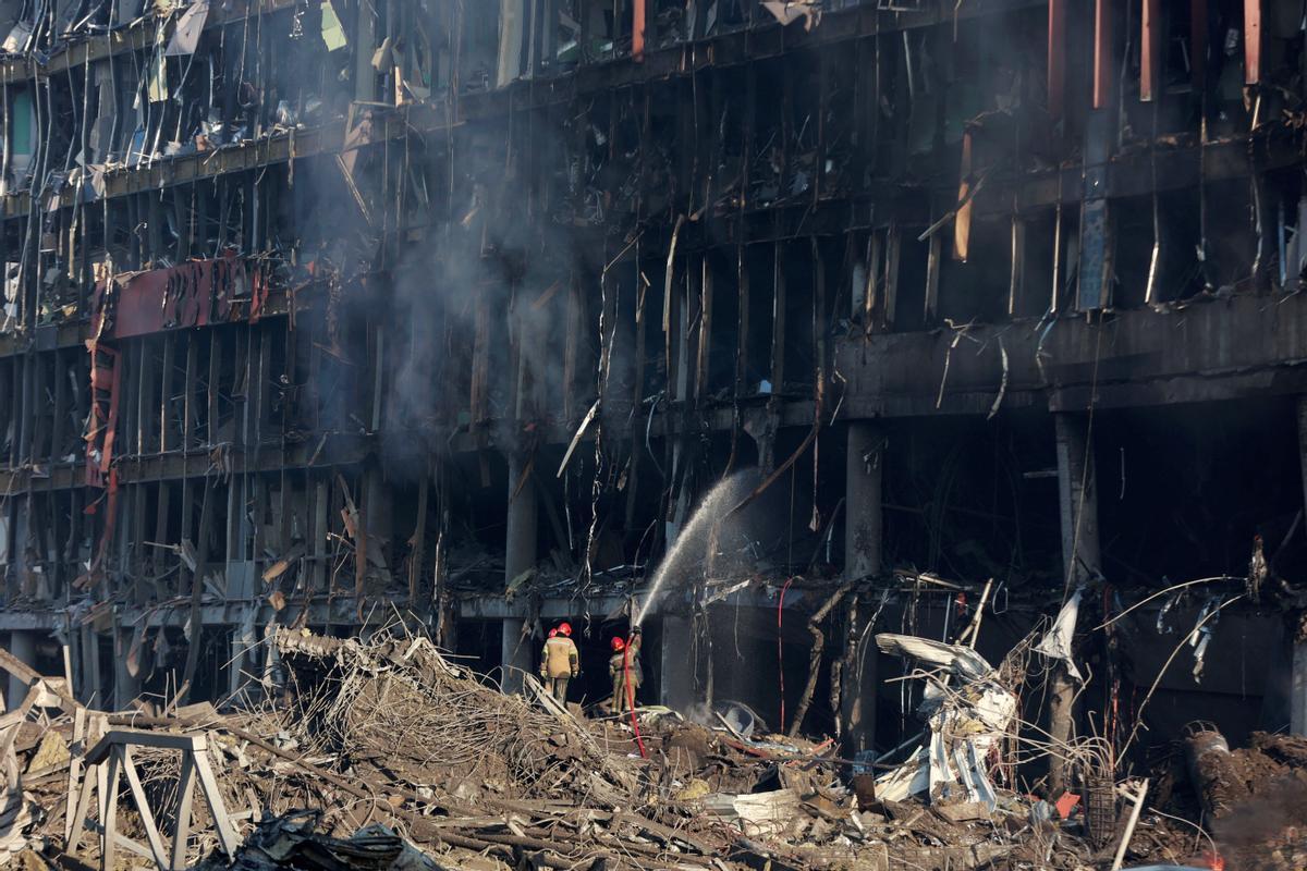 Los bomberos trabajan en el sitio de un ataque militar en un centro comercial en el distrito Podilskyi de Kiev,