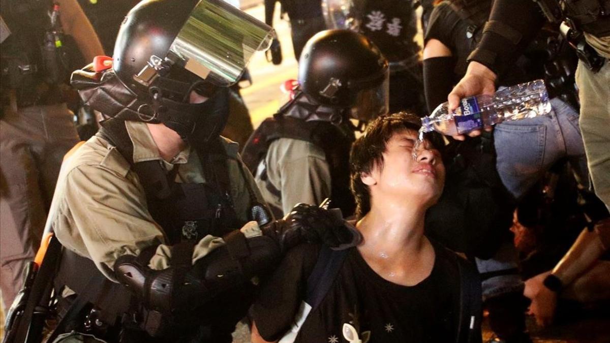 Oficiales de la policía antidisturbios vierten agua sobre un manifestante durante su detención en Hong Kong.