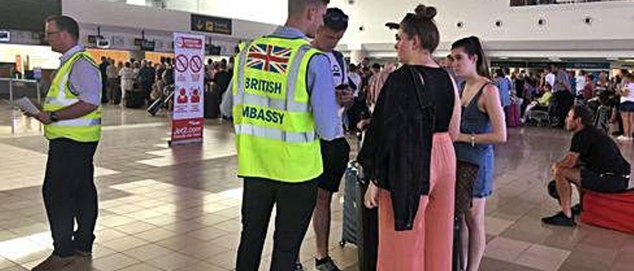 Un contratado de la embajada británica atiende a un grupo de turistas en el aeropuerto de Lanzarote.