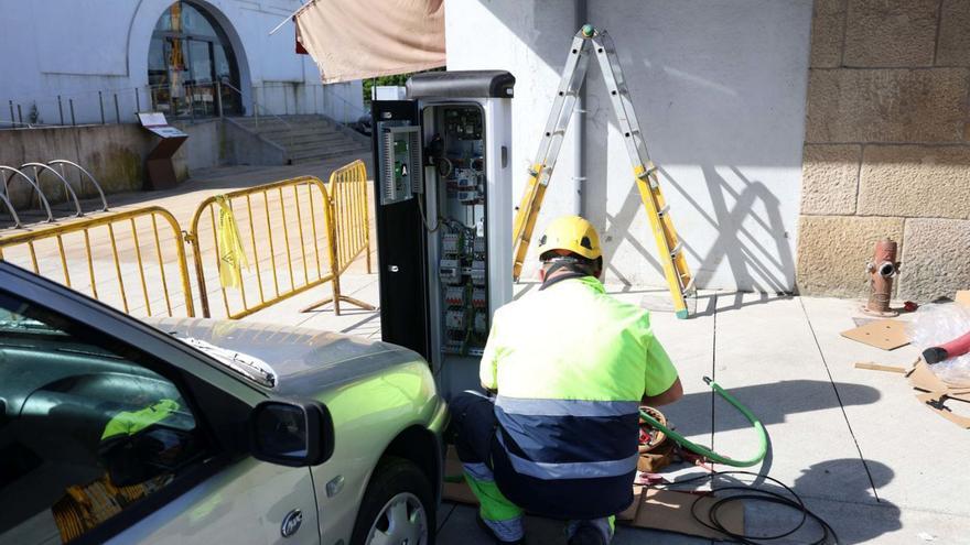 Un operario instalando un punto de recarga para coches eléctricos en la plaza de abastos de Vilagarcía.