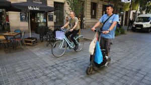 Un patinete y una bicicleta circulando por Consell de Cent