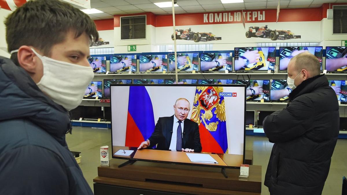 Clientes en una tienda observan la rueda de prensa del presidente Putin.