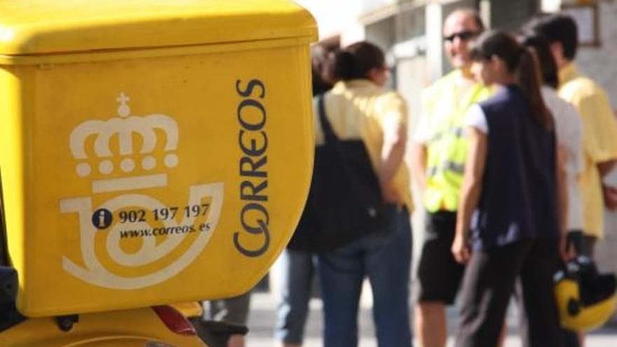 Una motocicleta de Correus amb uns treballadors al fons