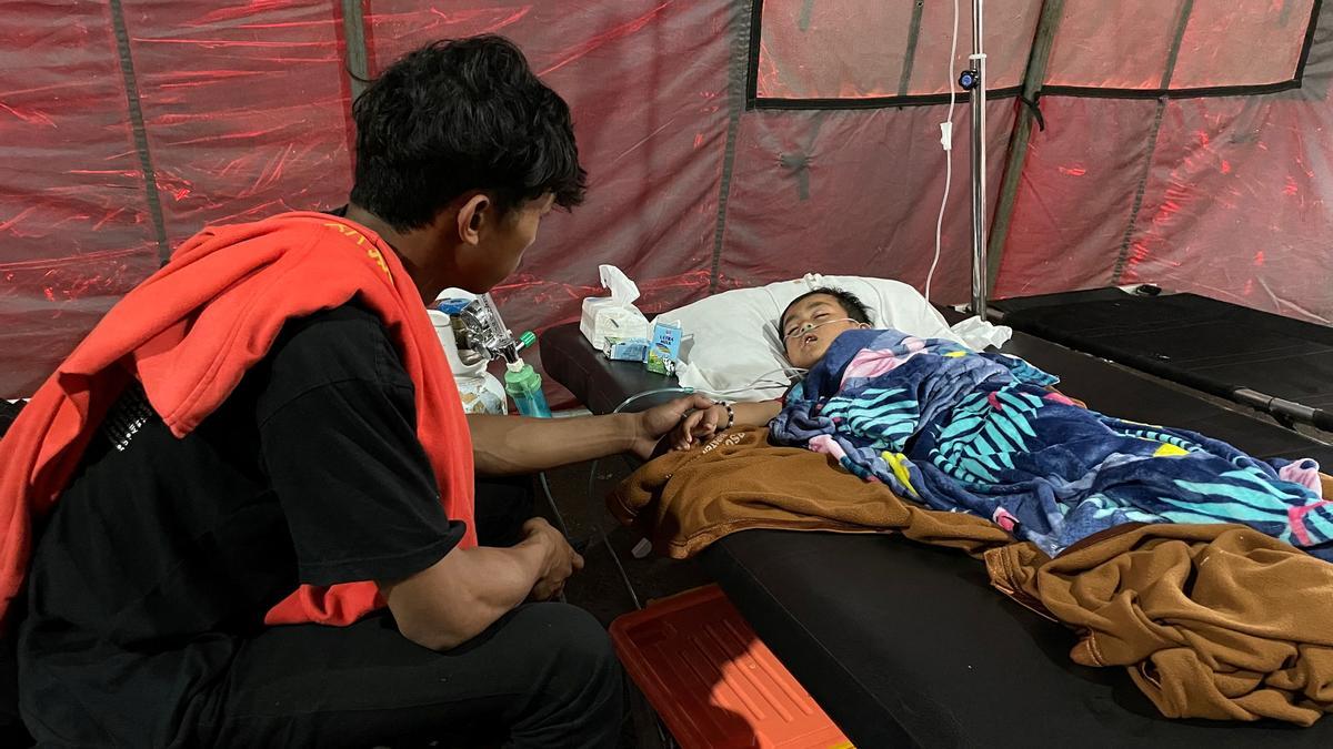 Salman Alfarisi, de 22 años, se sienta junto a su hermano pequeño Azka, de seis años, en una tienda de campaña de emergencia fuera del hospital en Cianjur, Indonesia.