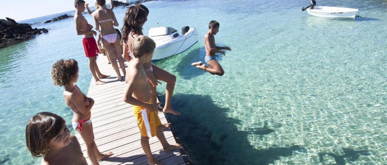 Un grupo de niños se lanzan al agua desde el embarcadero ubicado en la zona de El Puertito.