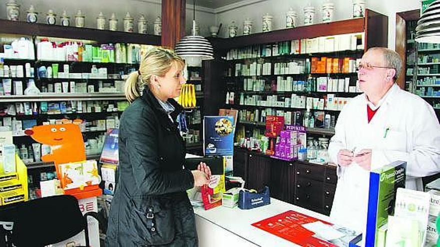 Un farmacéutico atiende a una clienta en una botica de Pola de Laviana.