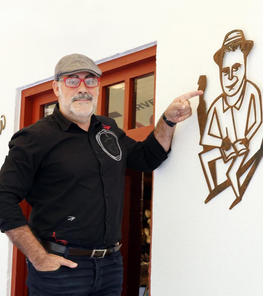 Carlos Blanco, a la entrada de la Taberna Eligio ante la caricatura de Domingo Villar.