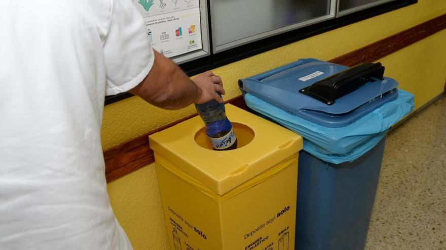 Un sanitario deposita una botella de plástico en un contenedor