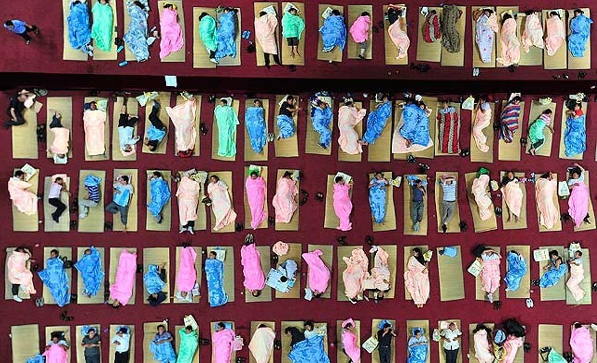 Pares d’alumnes de primer curs que han acompanyat els seus fills el primer dia de classe dormen en matalassos a terra al gimnàs de la Universitat de Huazhong, a Wuhan (Xina).