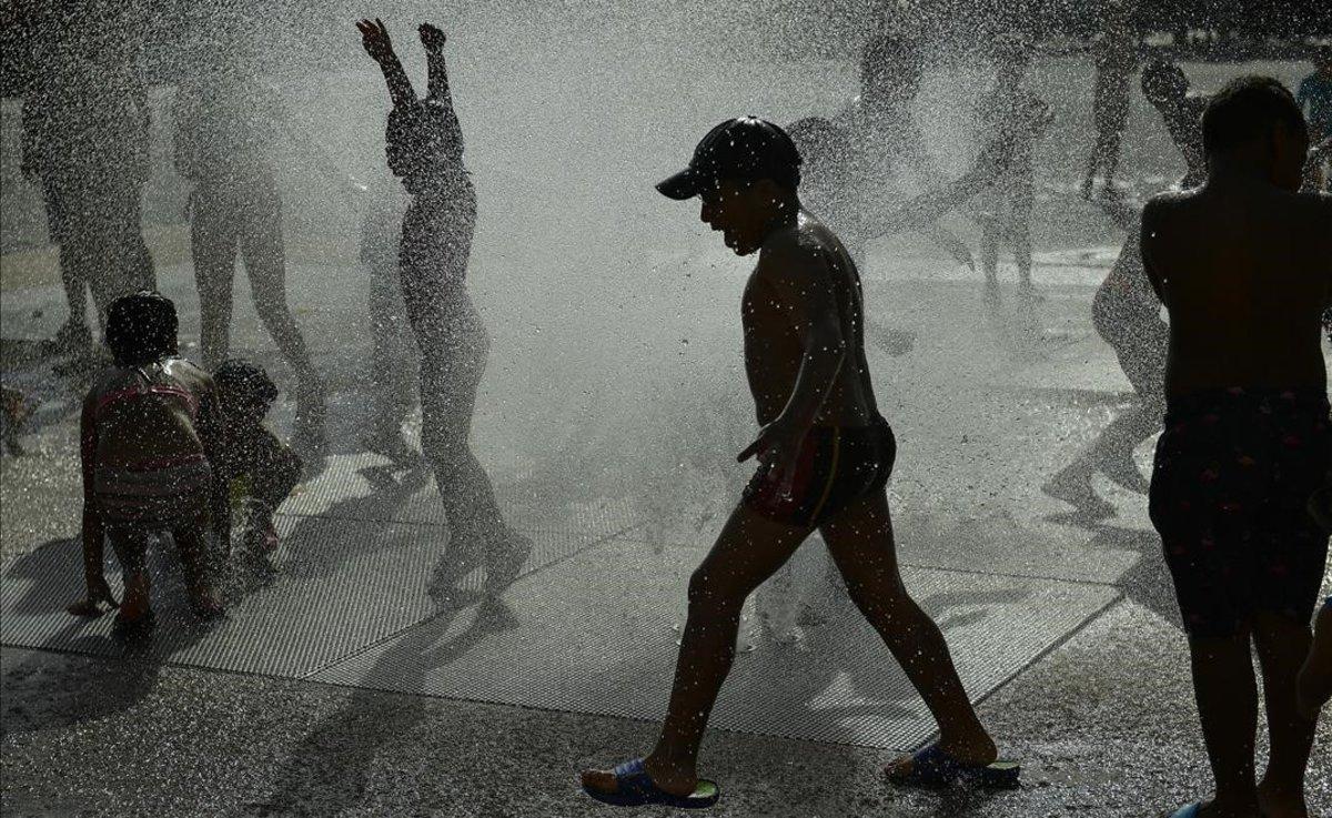 Niños se refrescan en una fuente en Pamplona.