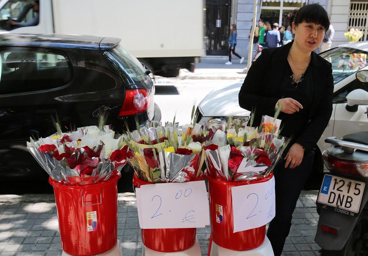 Una mujer vende rosas a 2 euros delante de un comercio chino en la calle de Consell de Cent, en Barcelona.