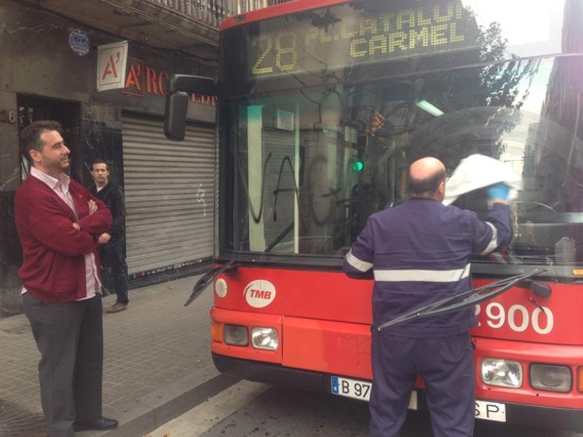 Un hombre limpia el parabrisas de un autobús pintado.