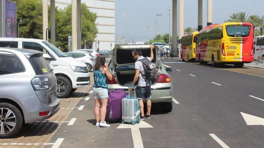 Unos turistas cargando un coche con su equipaje junto al parking gratuito.