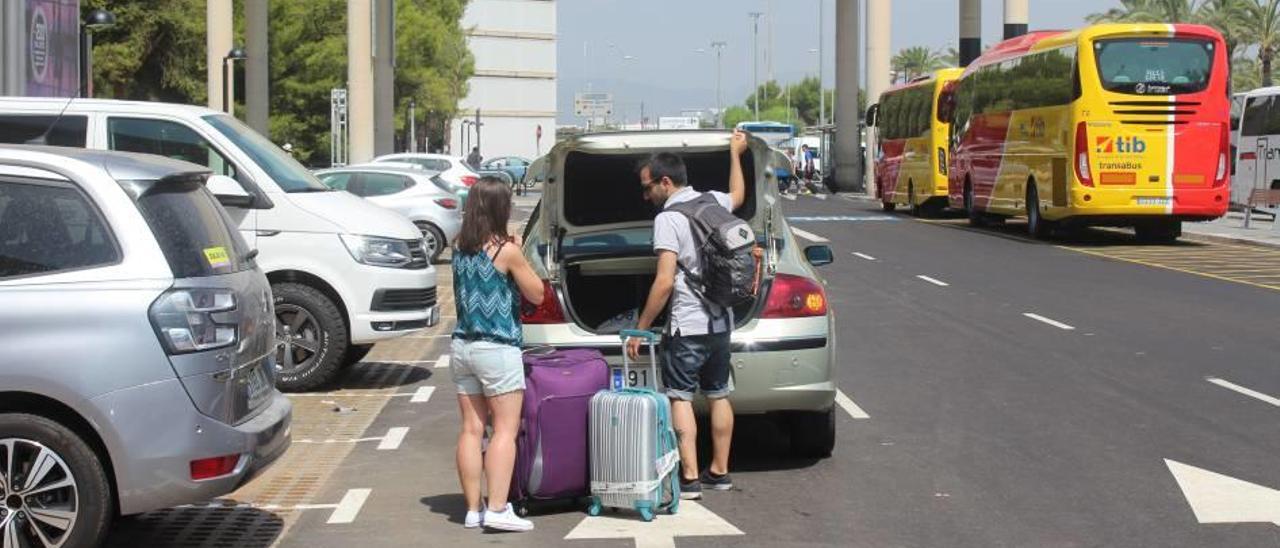 Unos turistas cargando un coche con su equipaje junto al parking gratuito.