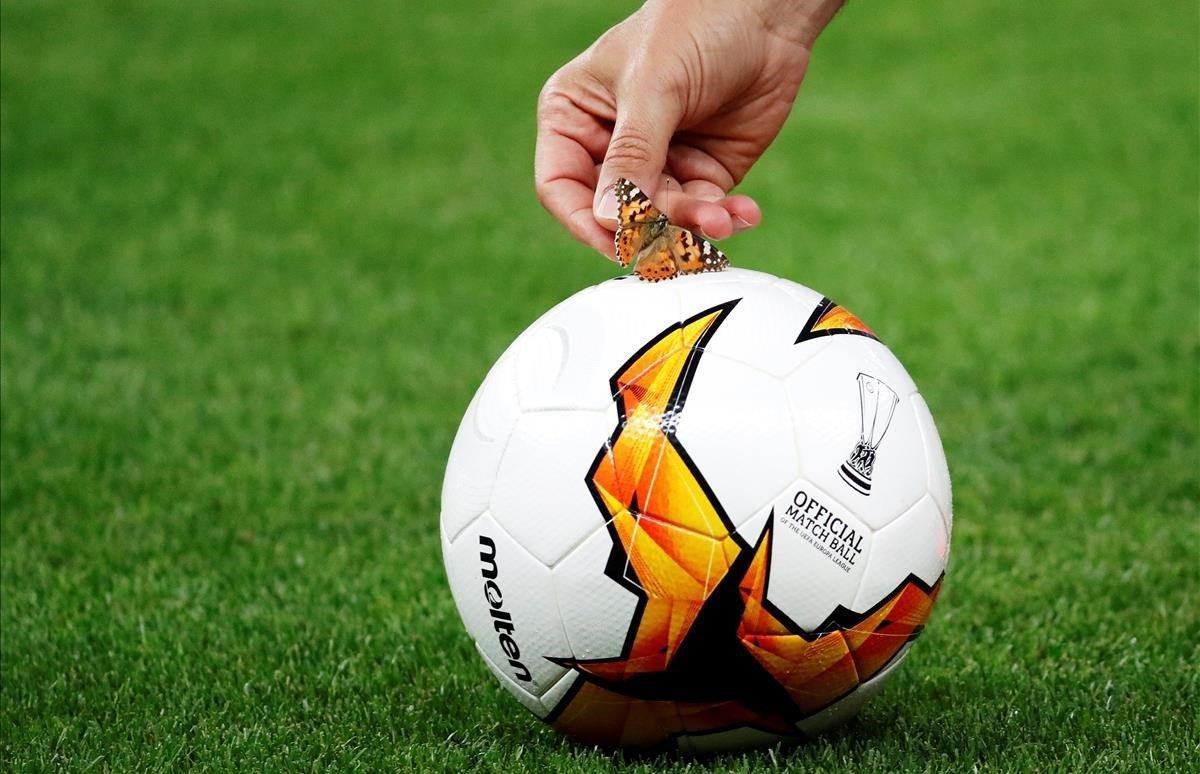 Un futbolista del Chelsea quita una mariposa del balón oficial durante una sesión de entrenamiento en el Estadio Olimpico de Baku, Azerbaiyán.