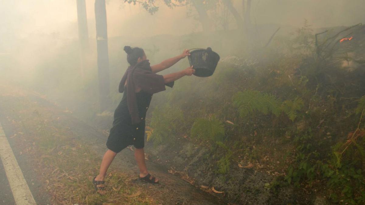 Una mujer tratando de sofocar las llamas con un capacho de agua. |   // N.P.