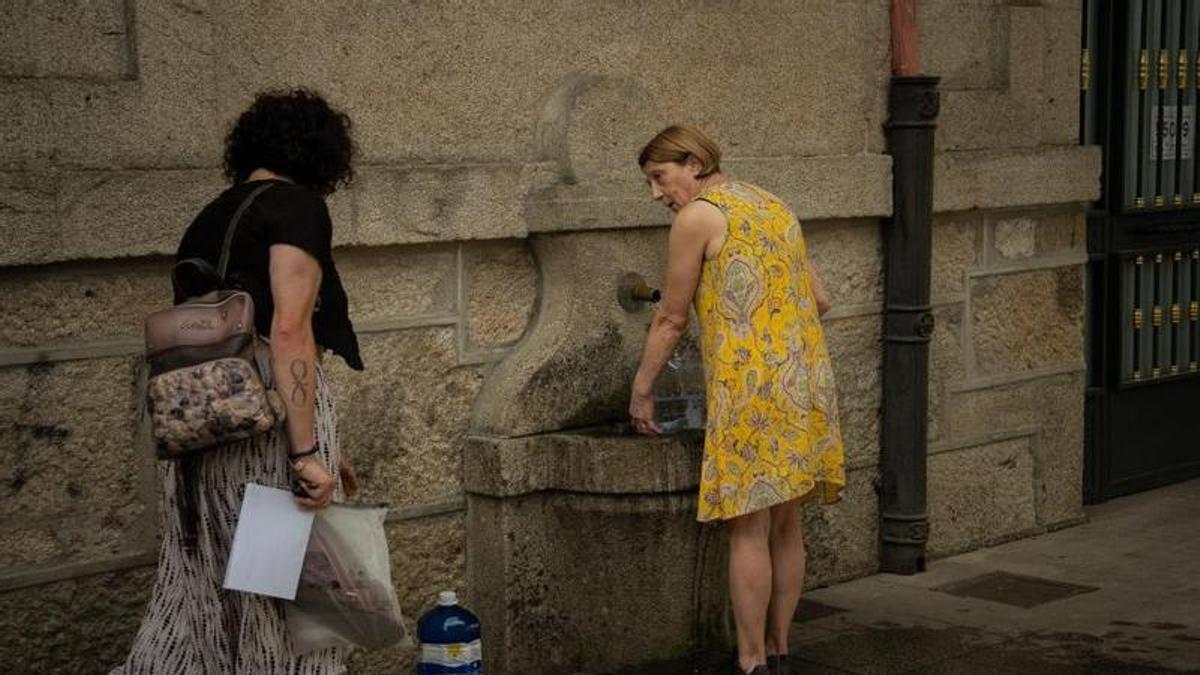 Dos mujeres rellenando garrafas de agua en Ourense durante una jornada de alerta roja por calor este verano.