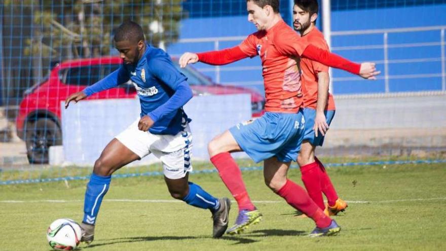 El jugador del Oviedo B Shaq, con el balón, perseguido por Juan Sánchez, del Colunga.