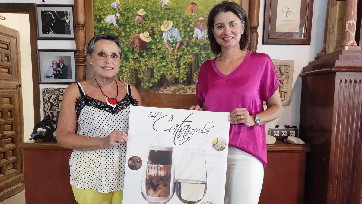 Carmen Flores y Paqui Herrador muestran el cartel del evento.