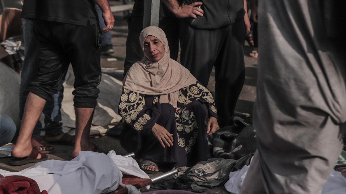 Una mujer observa los cuerpos de víctimas fallecidas por un bombardeo israelí en el exterior del Hospital Al Shifa de Gaza.