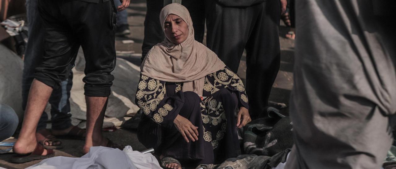 Una mujer observa los cuerpos de víctimas fallecidas por un bombardeo israelí en el exterior del Hospital Al Shifa de Gaza.