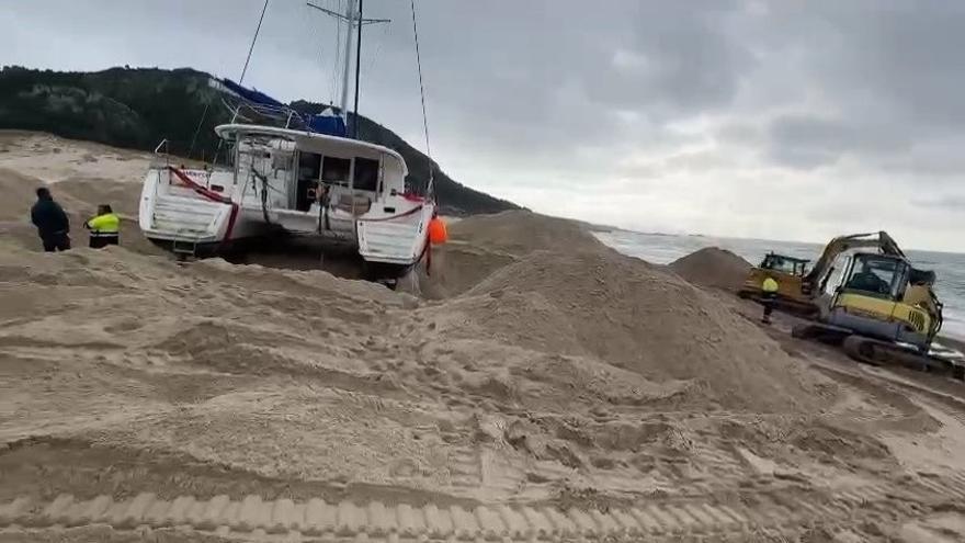 Dos excavadoras trabajan en la playa de Area Maior para retirar el catamarán que cruzó el Atlántico a la deriva