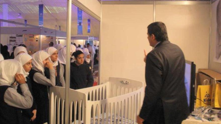 José María Artiaga muestra la cuna a un grupo de mujeres en la Feria de Kuwait.