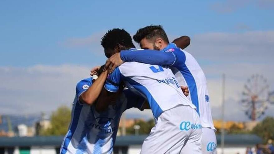 Nuha recibe la felicitación de dos compañeros del Atlético Baleares tras anotar el gol del 1-0.