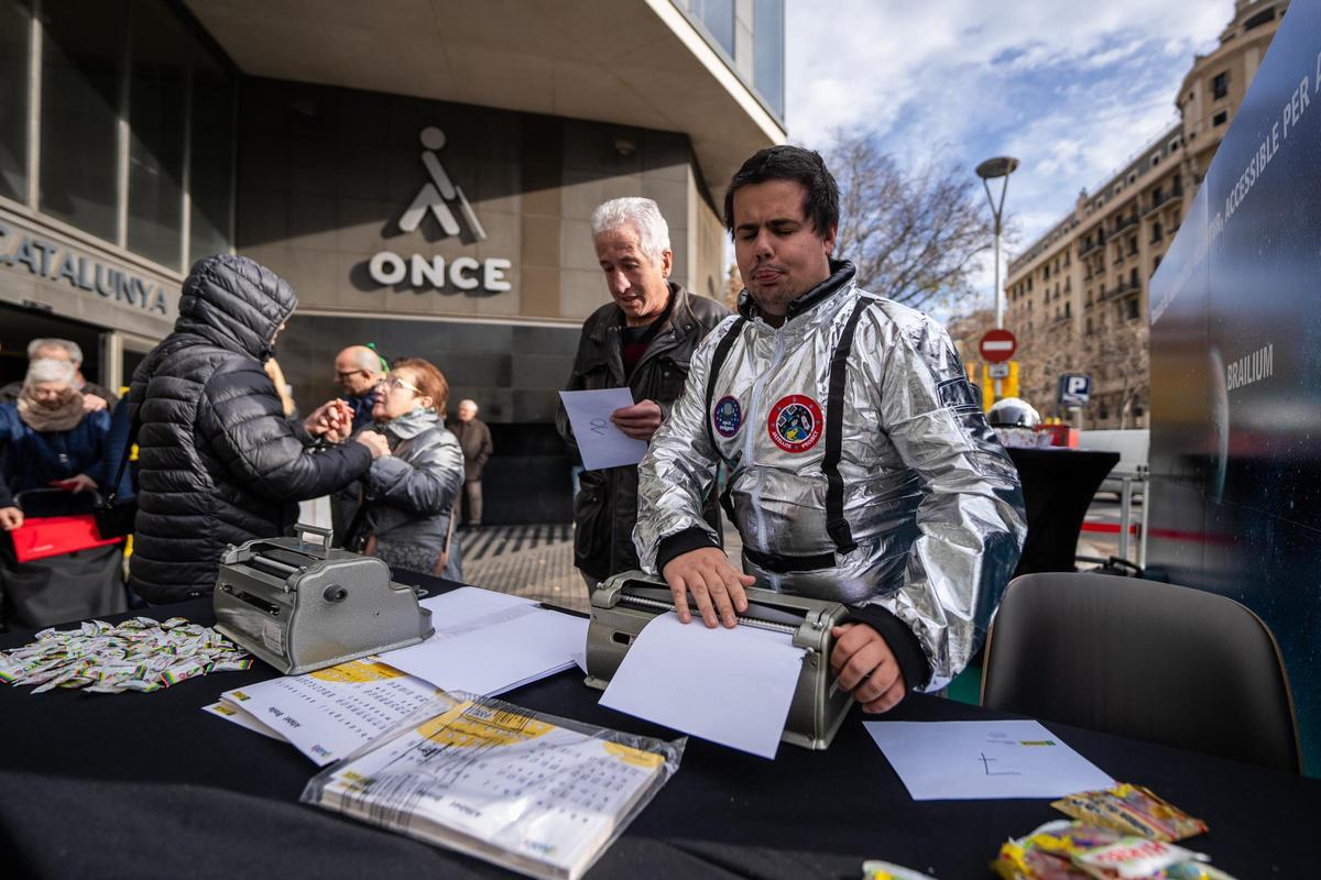 Un miembro de la ONCE, vestido de astronauta, manipula una máquina Perkins.