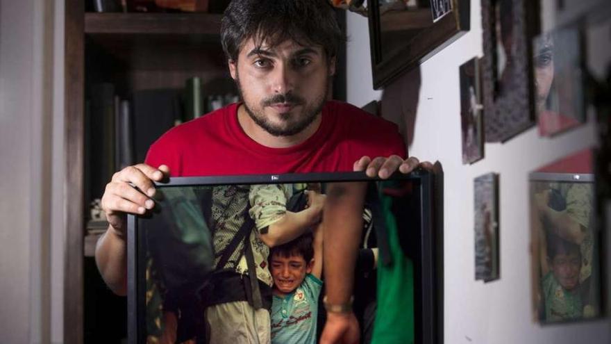 Óscar Pinal, en su casa de Ourense posando con una de sus fotografías sobre la crisis de refugiados. // Brais Lorenzo