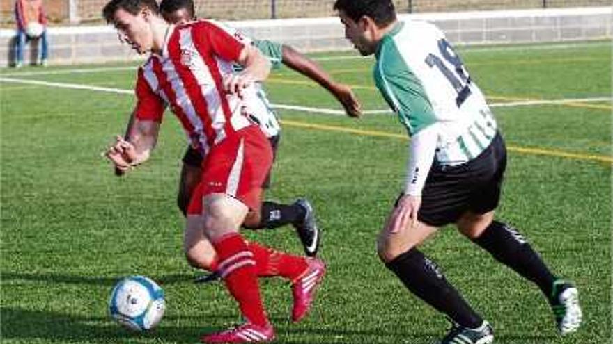 El jugador del Girona B David Bigas s&#039;endú la pilota davant la pressió de Segio Garcia i Tidian.