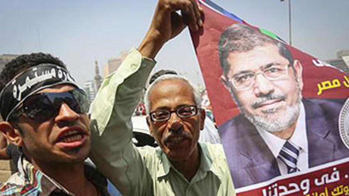 Dos simpatizantes de los Hermanos Musulmanes, Mohamed Mursi, sujetan un cartel electoral en la celebración en Tahrir, este lunes