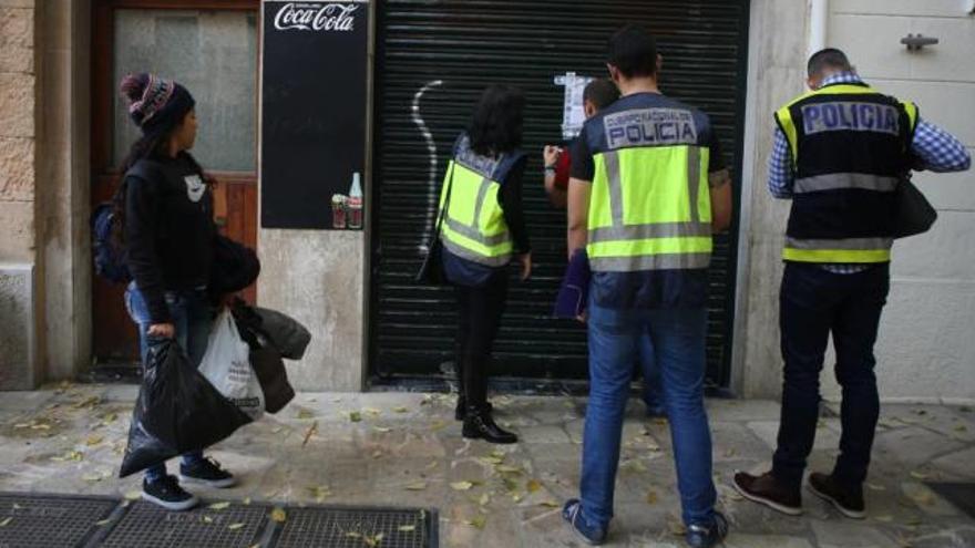 Una camarera mira cómo precintan el bar en el que trabaja.