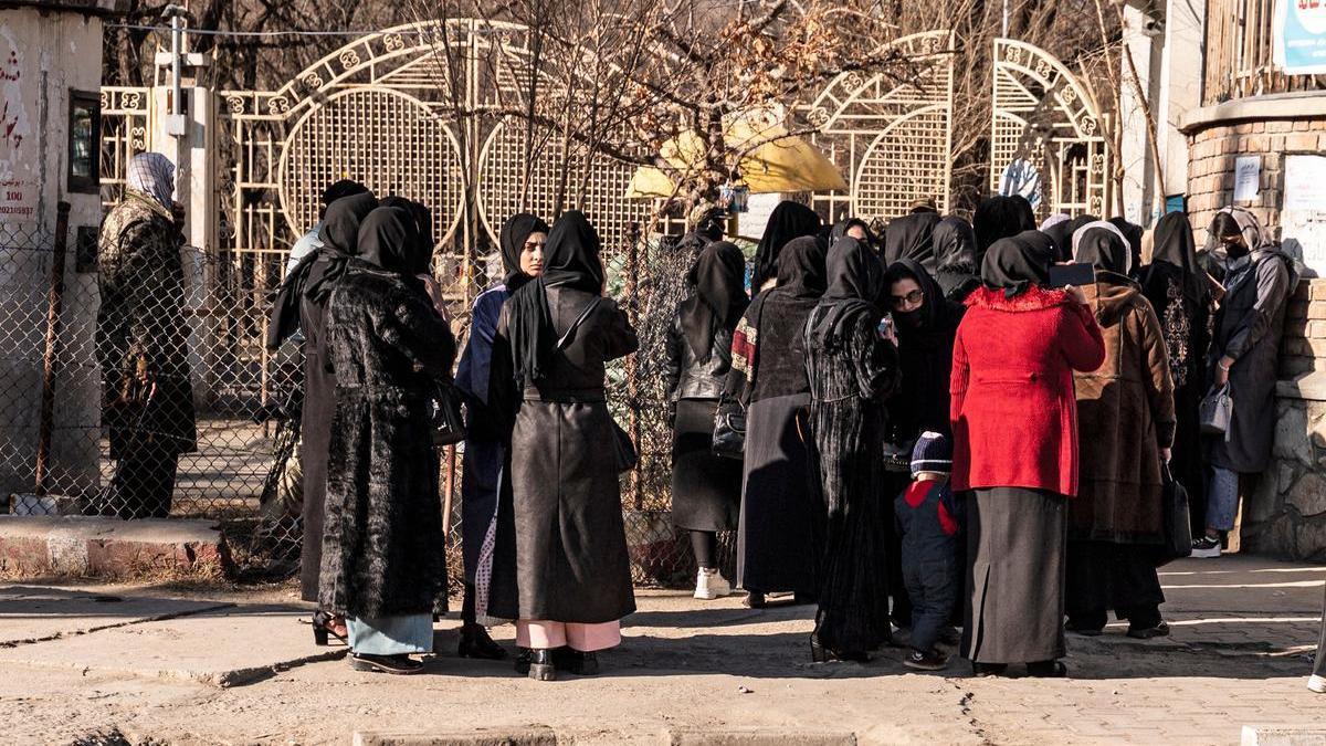 Mujeres afganas en la puerta de la universidad, custodiada por soldados, en Kabul.