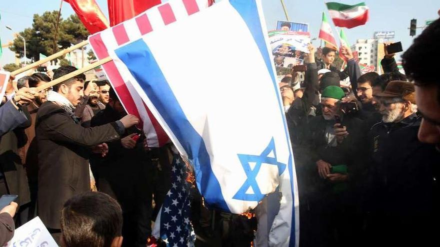 Manifestantes progubernamentales queman banderas estadounidenses e israelíes, ayer en la ciudad iraní de Mashhad. // AFP