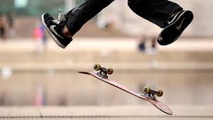 Un joven realiza piruetas mientras su tabla de skate gira por el aire en el Hyde Park de Sídney (Australia)