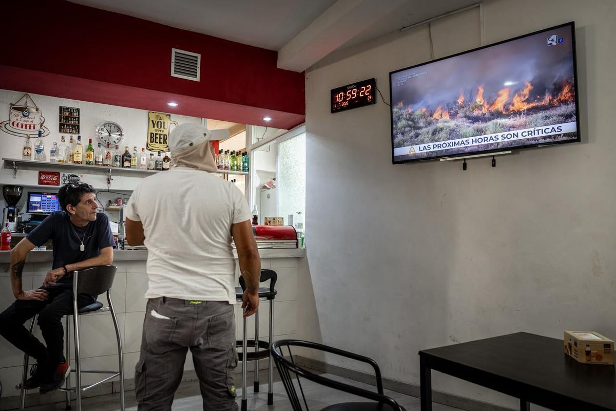 Varios vecinos de Robres siguen la evolución del fuego en la televisión, en un bar de la localidad.