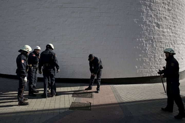 Policemen check a drain outside the Santiago Bernabeu stadium before the 'Clasico' soccer match between Real Madrid and Barcelona in Madrid, Spain