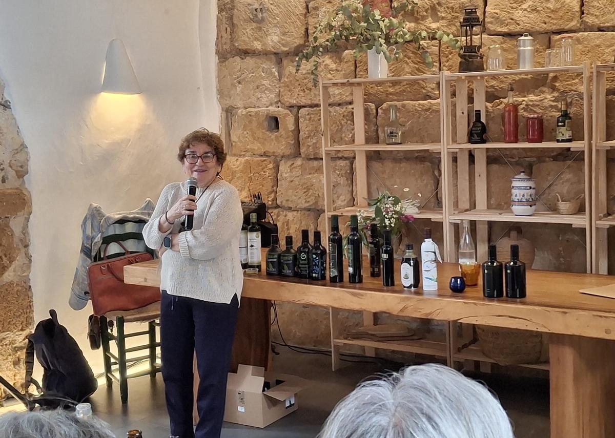 Roser Cabrera junto a todas las botellas de aceite de los productores que participaron en la feria