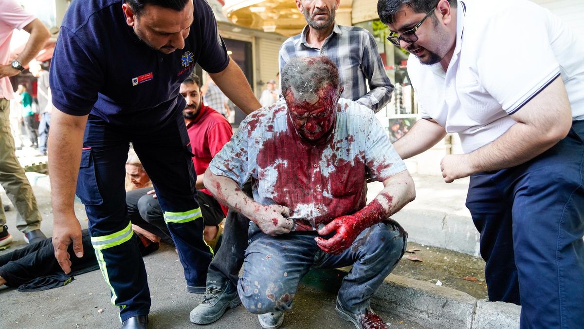Varias personas ayudan a un hombre herido en un ataque aéreo israelí en el centro de Teherán.