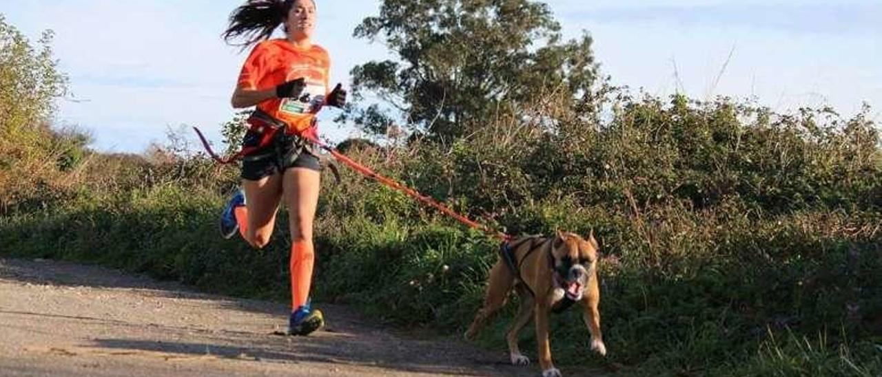 Una joven y su perro, practicando el canicross.