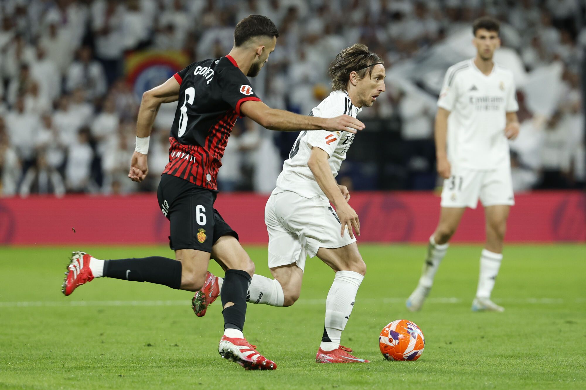 MADRID, 14/05/2025.- El centrocampista del Madrid Luka Modric (c) escapa de José Manuel Copete (i), del Mallorca, durante el partido de LaLiga de fútbol que Real Madrid y RCD Mallorca disputan este miércoles en el estadio Santiago Bernabéu. EFE/Chema Moya