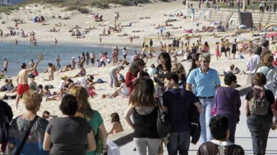 Personas disfrutando del sol y la buena temperatura ayer en el paseo y en la playa viguesa de Samil. // José Lores