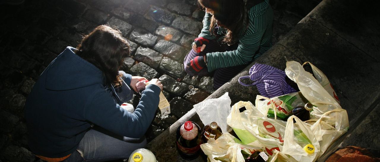 Dos jóvenes se sirven bebidas alcohólicas en un botellón.