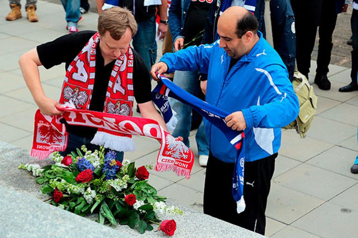 Dos representants dels aficionats russos i polonesos deixen bufandes de les seves respectives seleccions i un ram de flors, en un monument dins del cementiri militar soviètic, a Varsòvia.