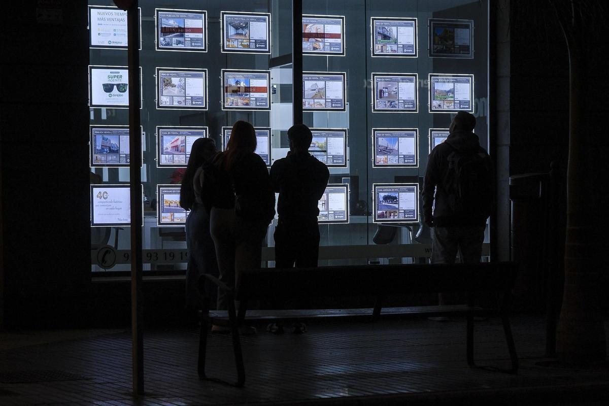 Varias personas miran los anuncios de casas en venta en una inmobiliaria